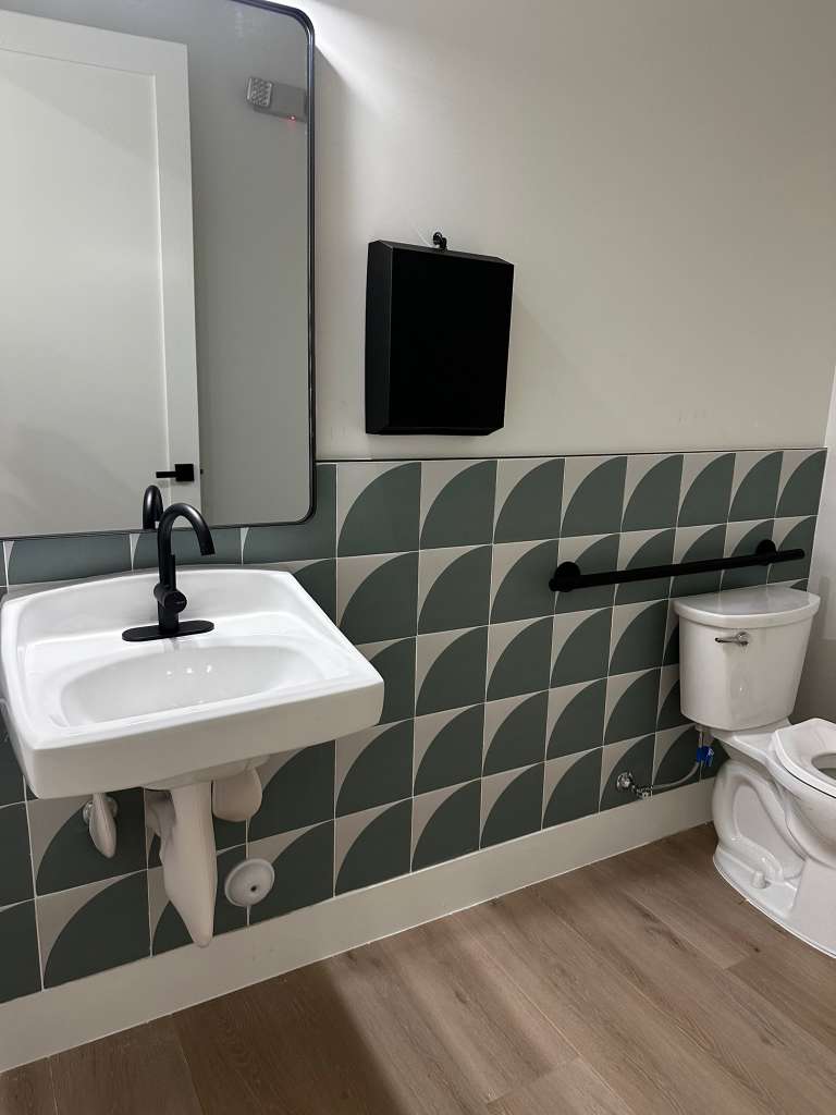 Clean bathroom with patterned tile, sink, and toilet after a deep cleaning service