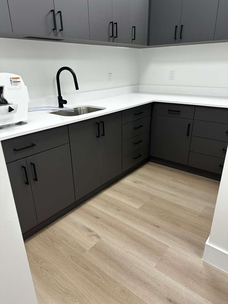 Clean office kitchenette with sink and cabinets maintained by our commercial cleaning team